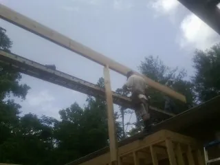 Carpenter setting a ridge beam over a new addition frame — Ice Dam Removal by Roofing Brothers in Homewood