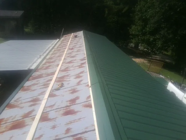 Old rusted panels beside newly installed green metal roofing — Wind Damage Roof Repair by Roofing Brothers in Homewood