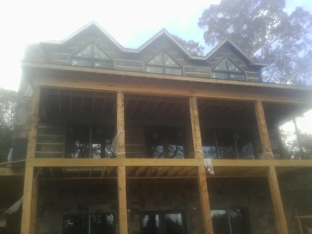 Dormers and porch framing on a large log home under construction — Roof Coating work by our crew in Homewood