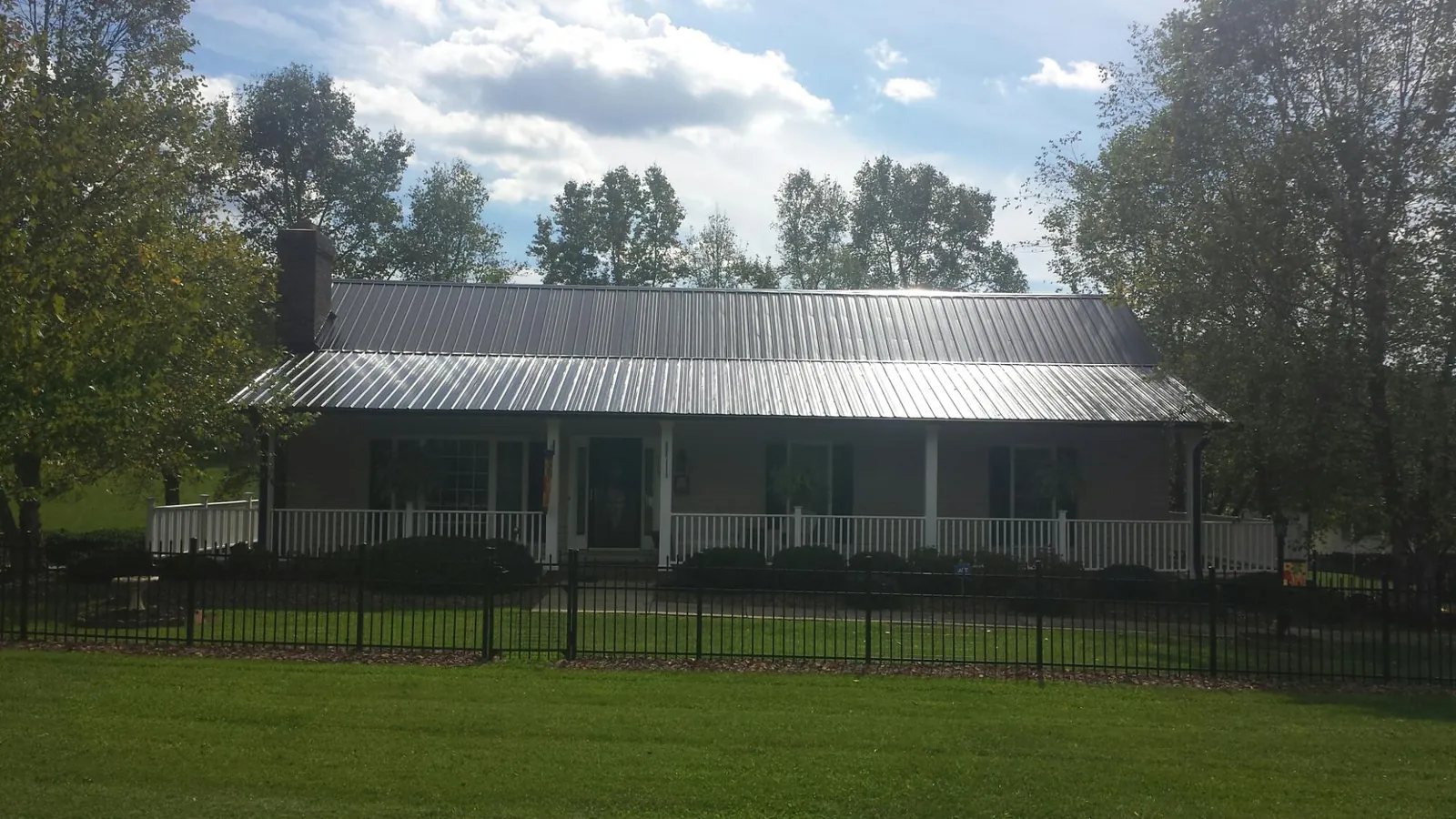 Gray metal roof on a brick ranch with a full width front porch — Gutter Guard Installation work by our crew in Homewood