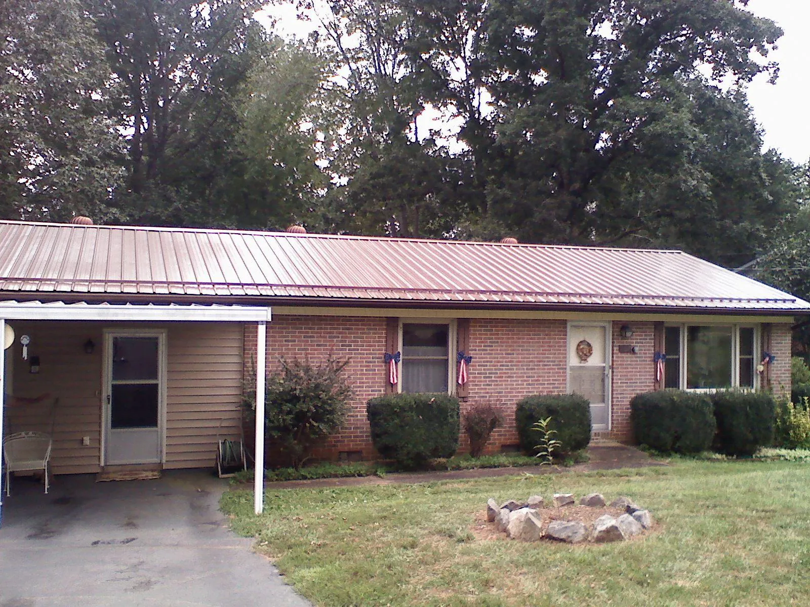 Bronze metal roof and carport on a brick ranch home — Roof Repair work by our crew in Homewood