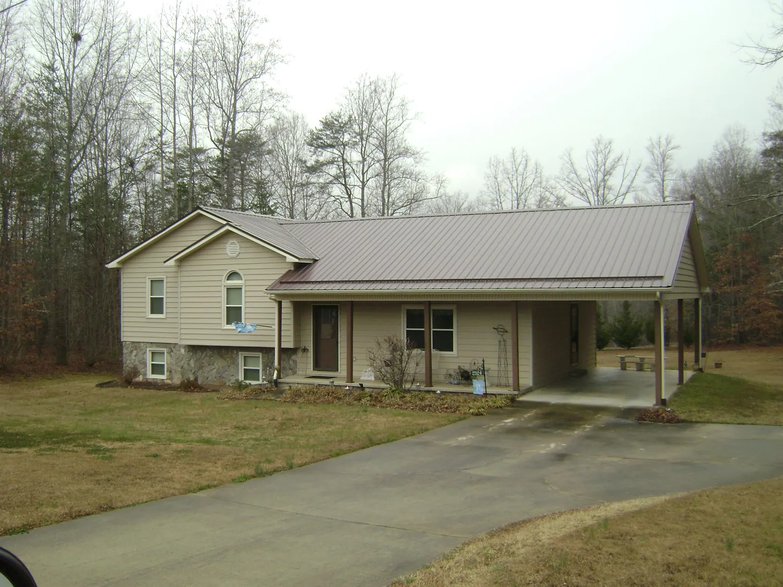 Brown metal roof on a tan split level home with an attached carport in Homewood