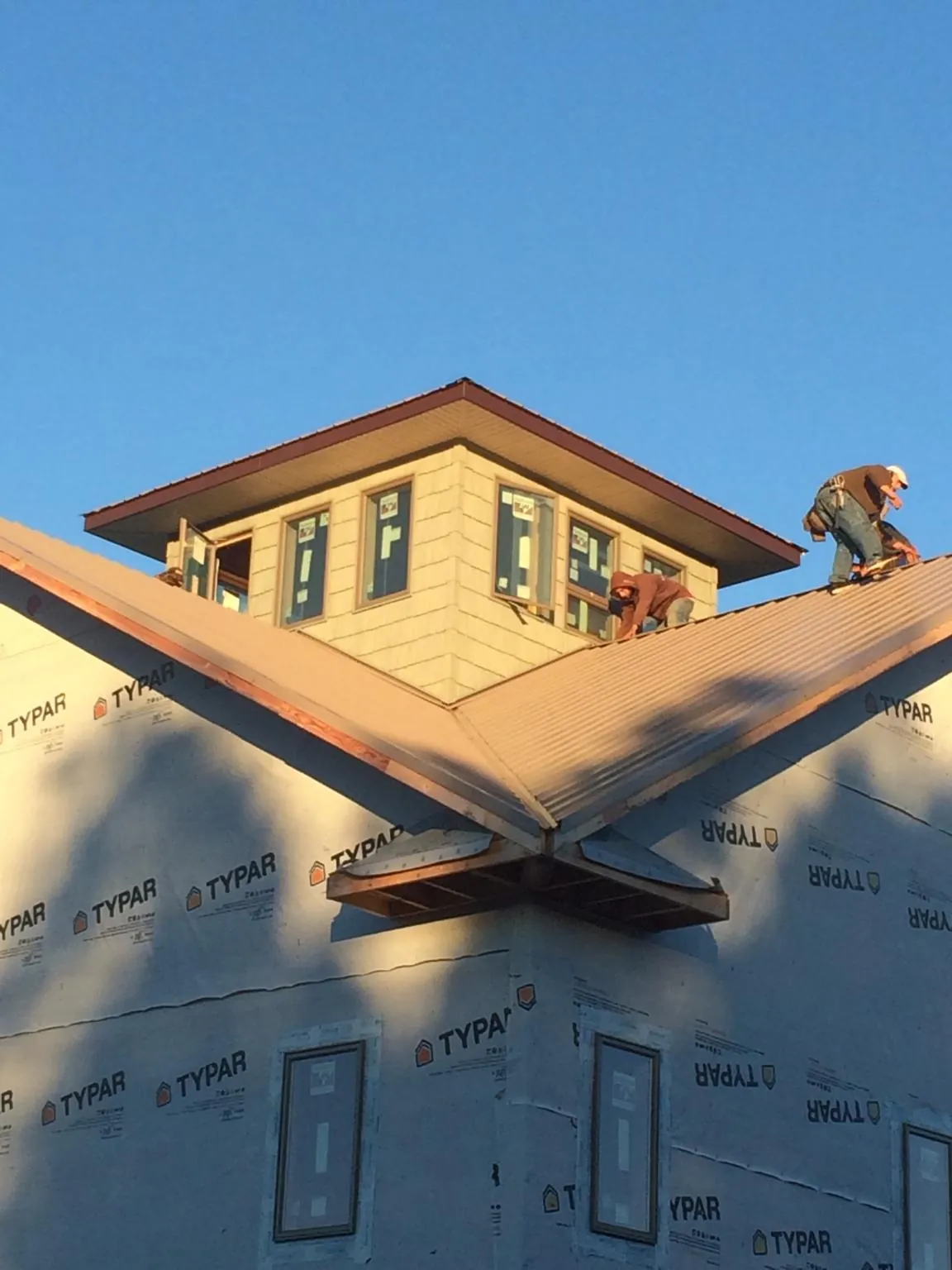 Roofers working around a rooftop cupola on a new metal roof at sunset — Roof Waterproofing in Homewood by Roofing Brothers